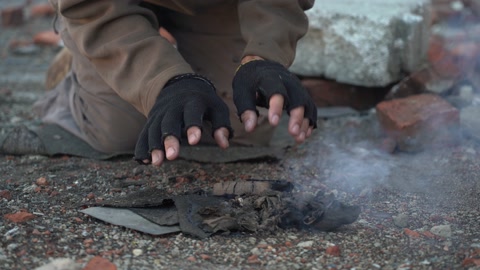 Homeless man warms his hands. Hands in black torn gloves Close …の動画素材