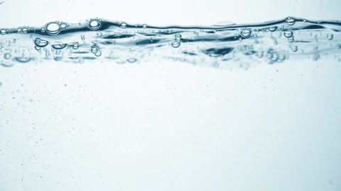 Clear water surface in slow motion, air bubbles, drop splashes and ripples after