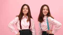 Happy little twin schoolgirls posing in uniform. Over pink [148121290] | 写真素材・ストックフォトのアフロ 