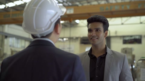 30s young Indian businessman in formal suit and hard hat having business talking