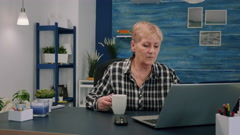 Old businesswoman sitting at workplace typing at laptop, drinking … [158342670] | 写真素材・ストックフォトのアフロ