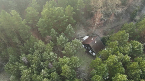 Beautiful aerial shot over remote rural cabin house in dense foggy woods