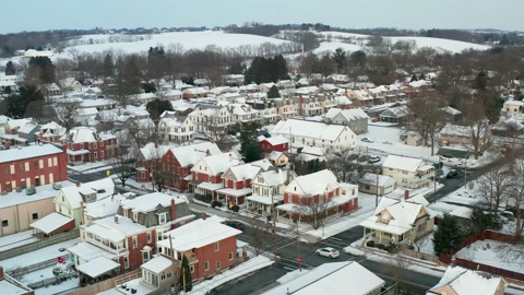 Descending aerial on small American town covered in winter snow. Traffic