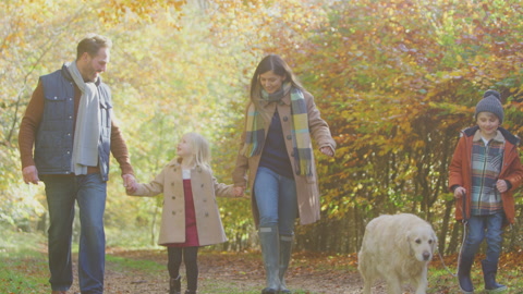 Family With Pet Golden Retriever Dog Walking Along Track In Autumn Countryside