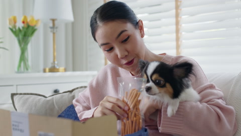 Asian woman happy unpack pet supply box at home shopping delivery.