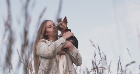 Young Woman Lovingly Hugs Pet Yorkie Dog While Looking Into Distance