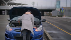 female driver is checking under hood space of her broken car, … [163728391] | 写真素材・ストックフォトのアフロ