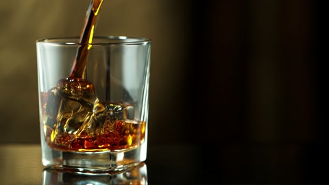 Super slow motion of pouring whiskey into glass, speed ramp effect