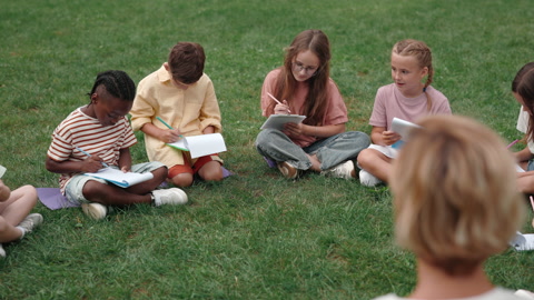 Multi ethnic children enjoying outdoors lesson with teacher