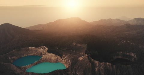 Beautiful orange sunset over Kelimutu volcanic mount, brown rock formations in