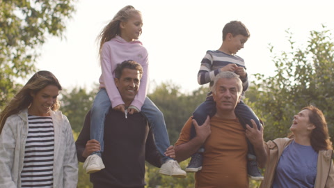 Tracking Shot of Children Sitting On Their Parents and Grandparents Shoulders 02