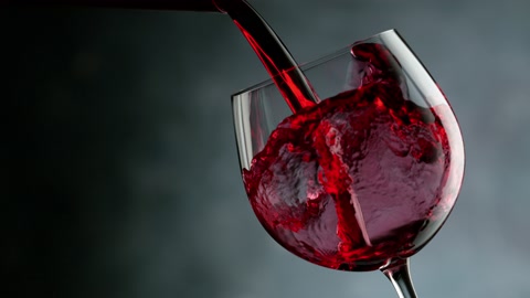 Super slow motion of pouring red wine into glass in detail, speed ramp effect