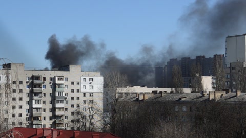 There is black smoke from a rocket or bomb explosion in a city during a war