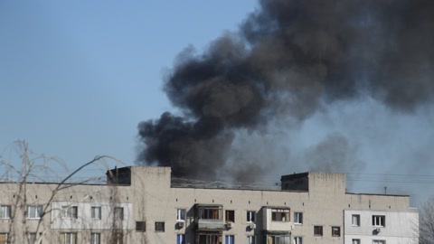 There is black smoke from a rocket or bomb explosion in a city during a war