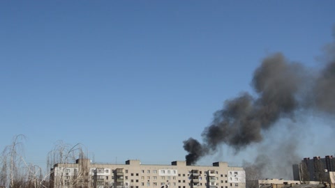 There is black smoke from a rocket or bomb explosion in a city during a war