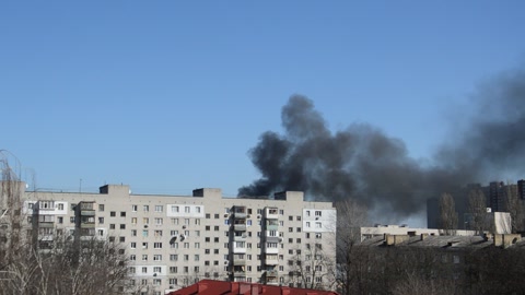 There is black smoke from a rocket or bomb explosion in a city during a war