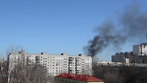 There is black smoke from a rocket or bomb explosion in a city during a war