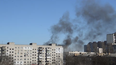 There is black smoke from a rocket or bomb explosion in a city during a war