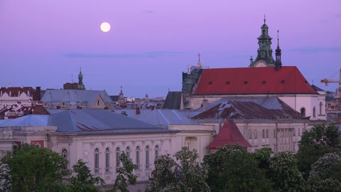 2022 - beautiful full moonrise over the rooftops and classical buildings in