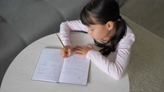 Top view schoolkid sit at desk write in notebook. The preteen … [200983178] | 写真素材・ストックフォトのアフロ 