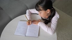 Top view schoolkid sit at desk write in notebook. The preteen … [200983178] | 写真素材・ストックフォトのアフロ