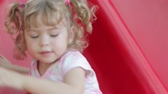 Beautiful little girl playing on a red slide at a playground [210388293] | 写真素材・ストックフォトのアフロ 