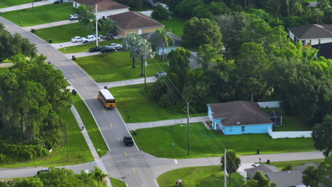 Top view of classical american yellow school bus driving on rural town street