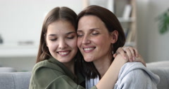 Mom and daughter sit on sofa embrace enjoy tender moment [212004450] | 写真素材・ストックフォトのアフロ
