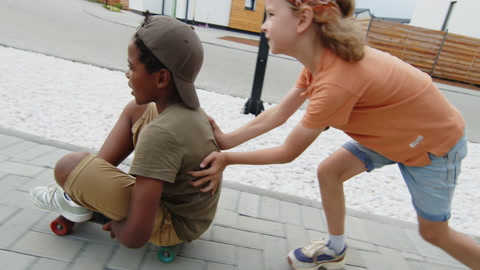 Two Mischievous Multiethnic Kids Playing with Skateboard Outdoors