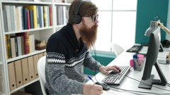 Young redhead man student using computer and headphones writing … [214775321] | 写真素材・ストックフォトのアフロ