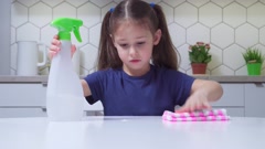 Amazing little preteen girl spraying on table with cleanser