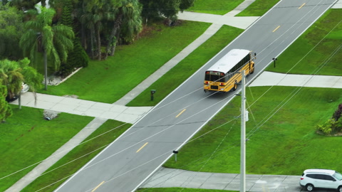 Top view of classical american yellow school bus driving on rural town street