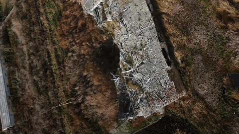 Vertical destroyed farm with explosion crater in real war in Ukraine