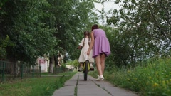 Loving mother supports little daughter learning to ride bicycle … [227032312] | 写真素材・ストックフォトのアフロ