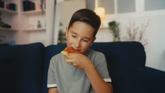 Pre-teen boy eating a slice of tasty pizza at home, enjoying … [248345407] | 写真素材・ストックフォトのアフロ